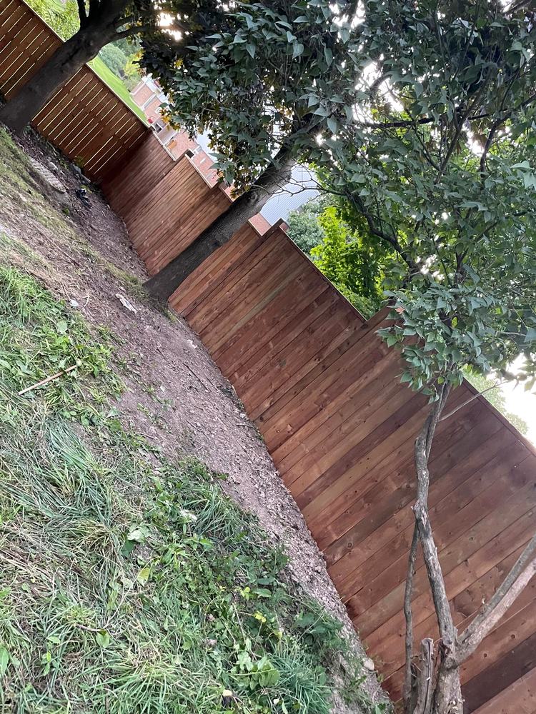 New stained privacy fence stepped down the slope