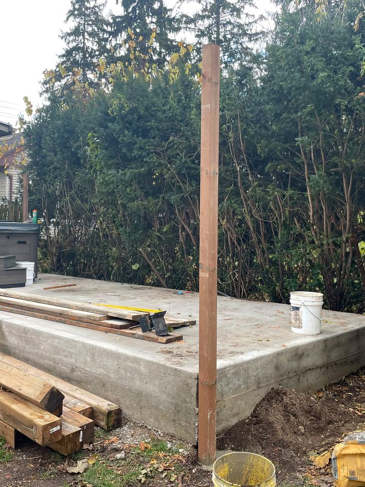 Posts and lumber staged on the concrete pad