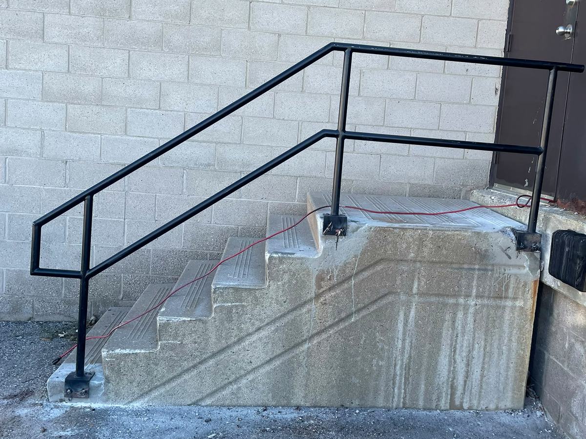 Concrete steps with new black metal railing installed