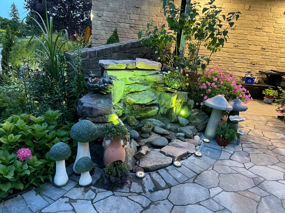 Backyard water feature with rock waterfall, plantings and garden ornaments
